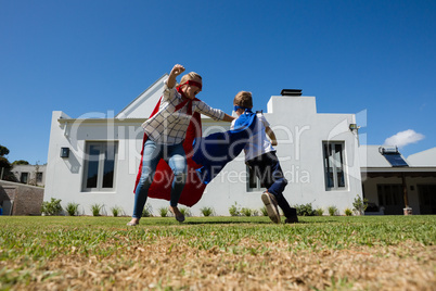 Mother and son in superhero costume playing in the backyard