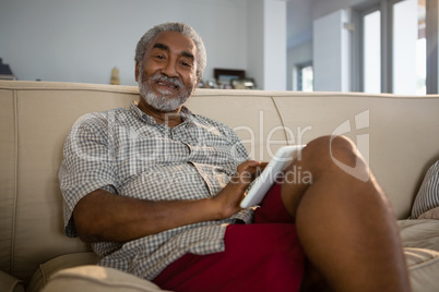 Senior man using digital tablet in the living room at home