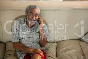 Senior man talking mobile phone in the living room