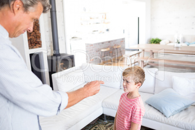 Angry father scolding his son in living room