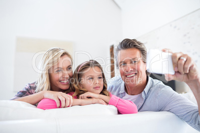 Happy family taking selfie on mobile phone in living room