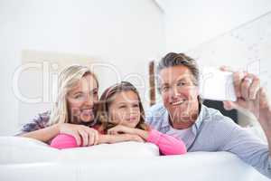 Happy family taking selfie on mobile phone in living room