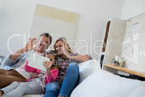 Family having a video call on digital tablet in living room