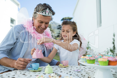 Smiling father and daughter in fairy costume having a tea party