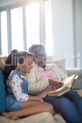 Grandmother and daughter reading book in living room