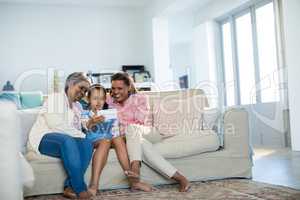 Happy family using digital tablet in living room