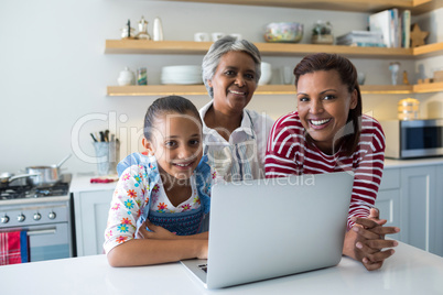 Happy family standing near kitchen worktop with laptop