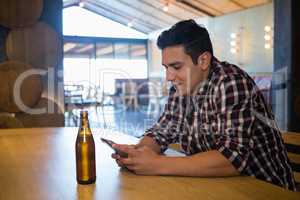 Man with beer bottle using phone