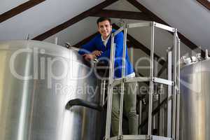 Portrait of young man standing by storage tank