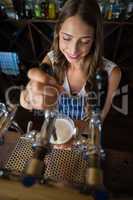 Beautiful barmaid pouring beer from tap in glass