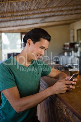 Young man using phone at bar counter