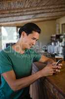 Young man using phone at bar counter