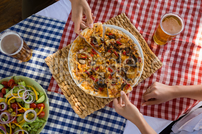 Cropped hands on friends having pizza at table