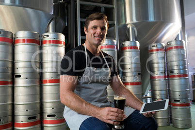 Portrait of worker holding tablet and beer at warehouse