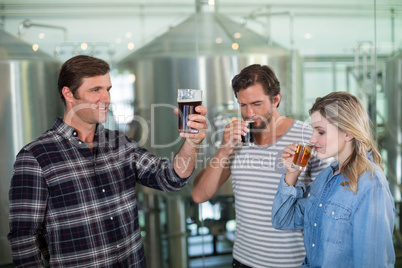 Friends tasting beer at factory