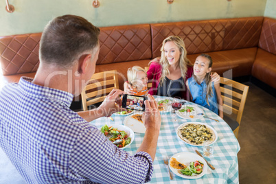 High angle view of father photographing family at restaurant