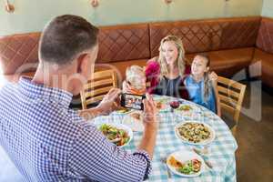 High angle view of father photographing family at restaurant