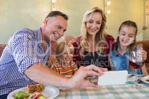 Father taking selfie with family at restaurant