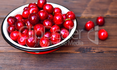 Ripe red cherry in an iron bowl