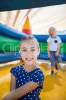 Girl sitting on bouncy castle while brother playing in background