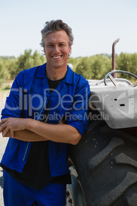 Worker leaning with arms crossed near tractor