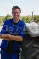 Worker leaning with arms crossed near tractor