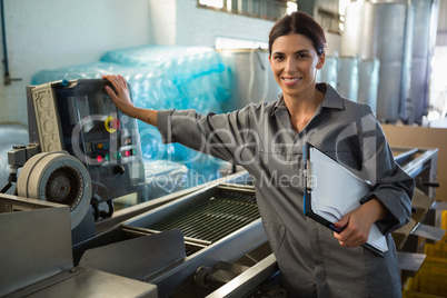 Woman with clipboard standing near machine