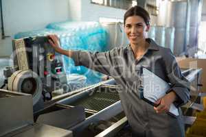 Woman with clipboard standing near machine