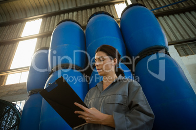 Female worker writing on clipboard in olive factory