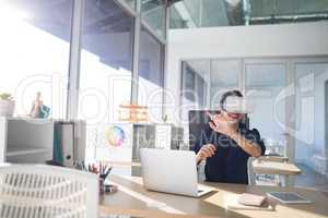 Female executive using virtual reality headset at her desk