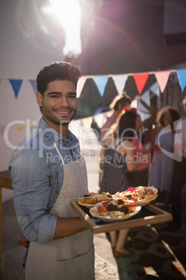 Happy waiter holding food in tray