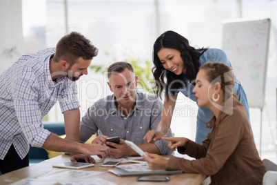 Team of executives discussing over digital tablet in the office