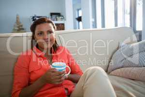 Woman having coffee in the living room at home