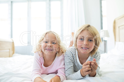 Happy siblings relaxing on bed in bedroom