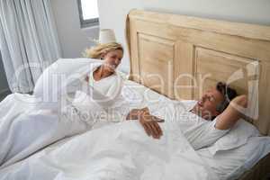 Woman getting irritated while man snoring on bed