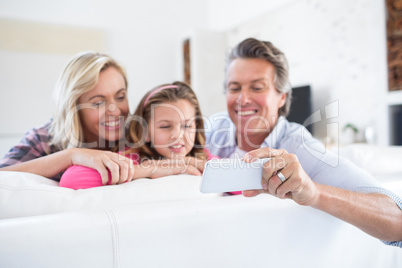 Happy family taking selfie on mobile phone in living room