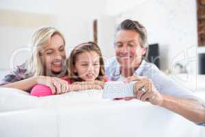 Happy family taking selfie on mobile phone in living room