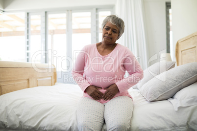 Senior woman having a huge stomach pain in bedroom