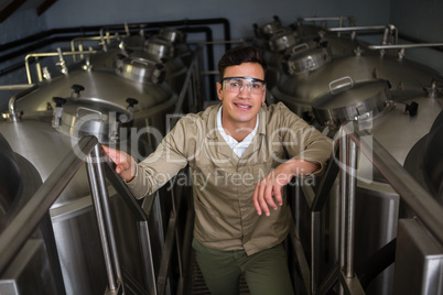 Portrait of worker amidst storage tanks at brewery