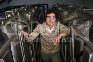 Portrait of worker amidst storage tanks at brewery