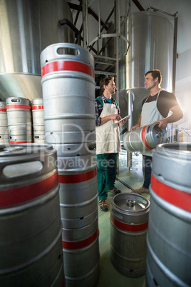 Coworkers discussing while standing by vats and kegs