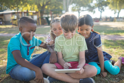 Boy using digital tablet while sitting with friends