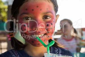 Portrait of girl with face paint having drink at park