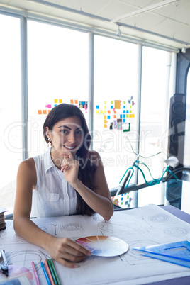 Female architect working on blueprint at her desk
