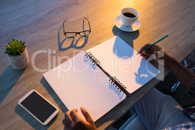 Male executive writing in diary at his desk