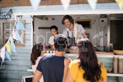 Smiling waiter giving order to customer at counter