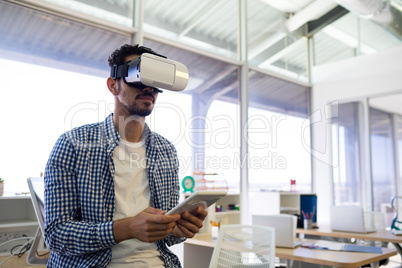 Male executive using virtual reality headset and digital tablet