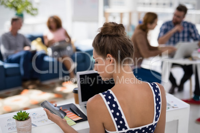 Female executive using mobile phone while working at desk