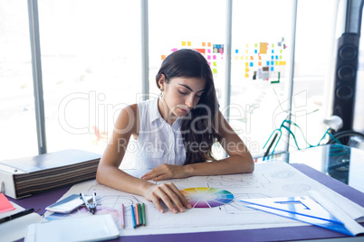 Female architect working on blueprint at her desk