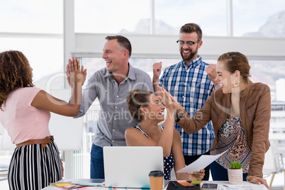 Team of executives giving high five to each other
